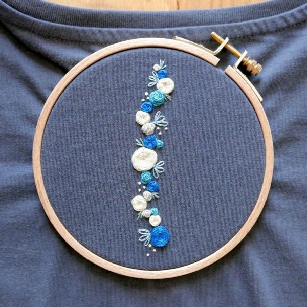 Artisan hand-stitching tee shirt embroidery on cotton fabric